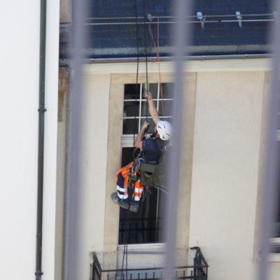 Arbeiter klettert am Seil aufs Dach