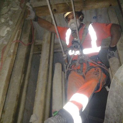 Arbeiter demontiert Gerüstholz aus Lüftungsschacht