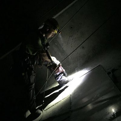 Arbeiter montiert Blech in engem Schacht am Seil