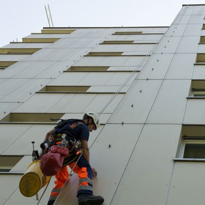 Seilarbeiter hängt an Fassade für spenglerarbeiten